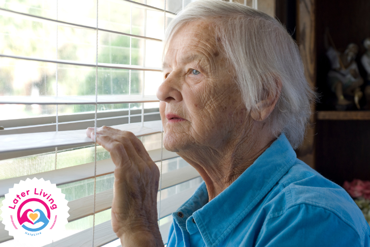 Elderly lady looking out of a window, reflecting on the difficult decision of being forced to sell her home for care costs.
