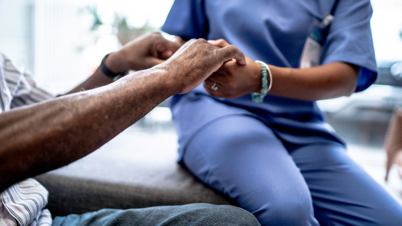 Elderly person's hands comforted by nurse illustrating UK's dementia care fee crisis